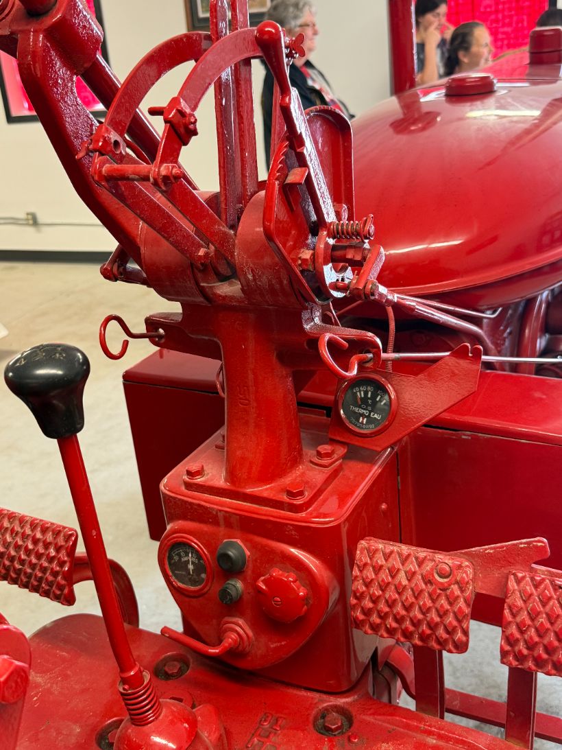 Close-up of a restored IH tractor's throttle, gauges, and control linkage