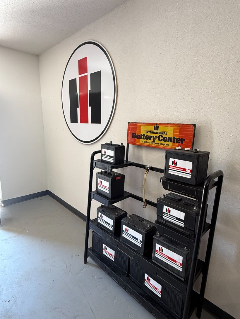 Large IH oval emblem on the wall above an International Battery Center rack